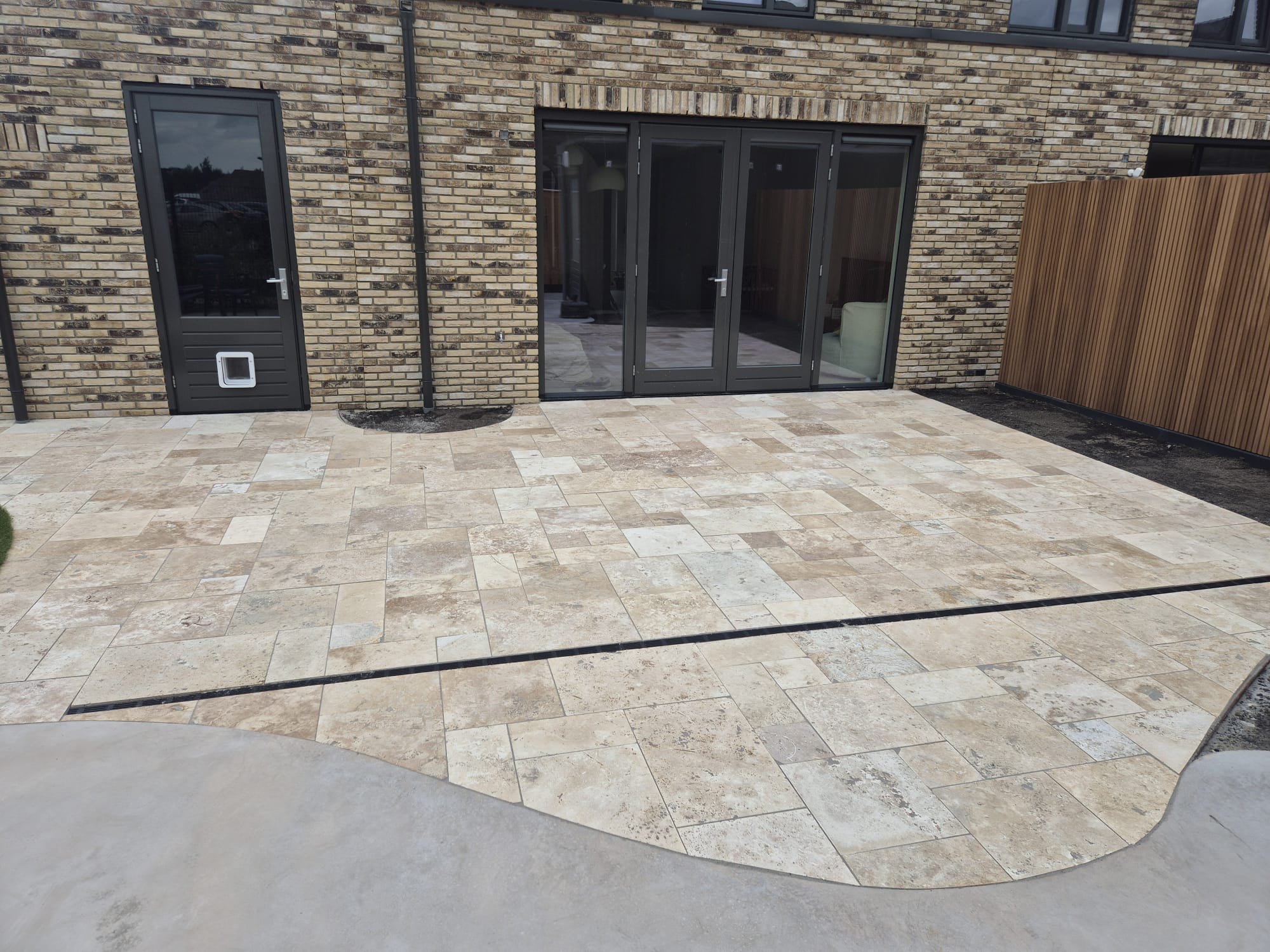Terras van travertin in romaans verband langs een modern huis